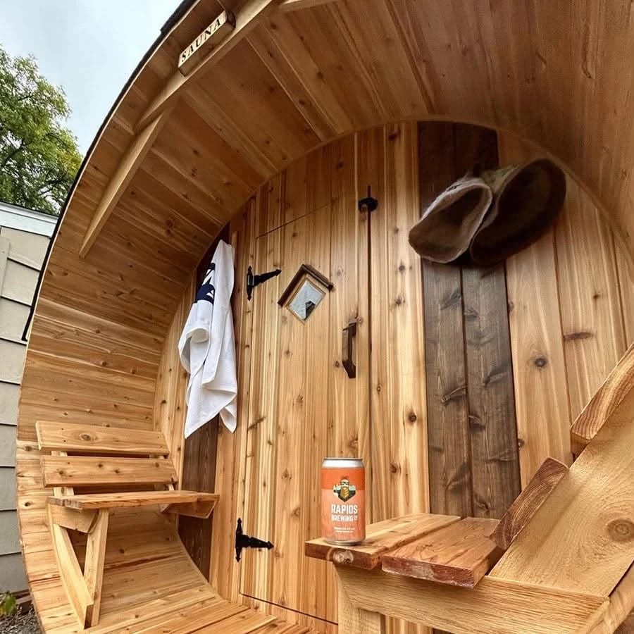 Porch of a cedar barrel sauna with a towel and sauna hats hanging by the door.